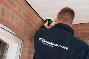 Monteur van CameraInstallatie.nl zet een camera vast onder een overstek