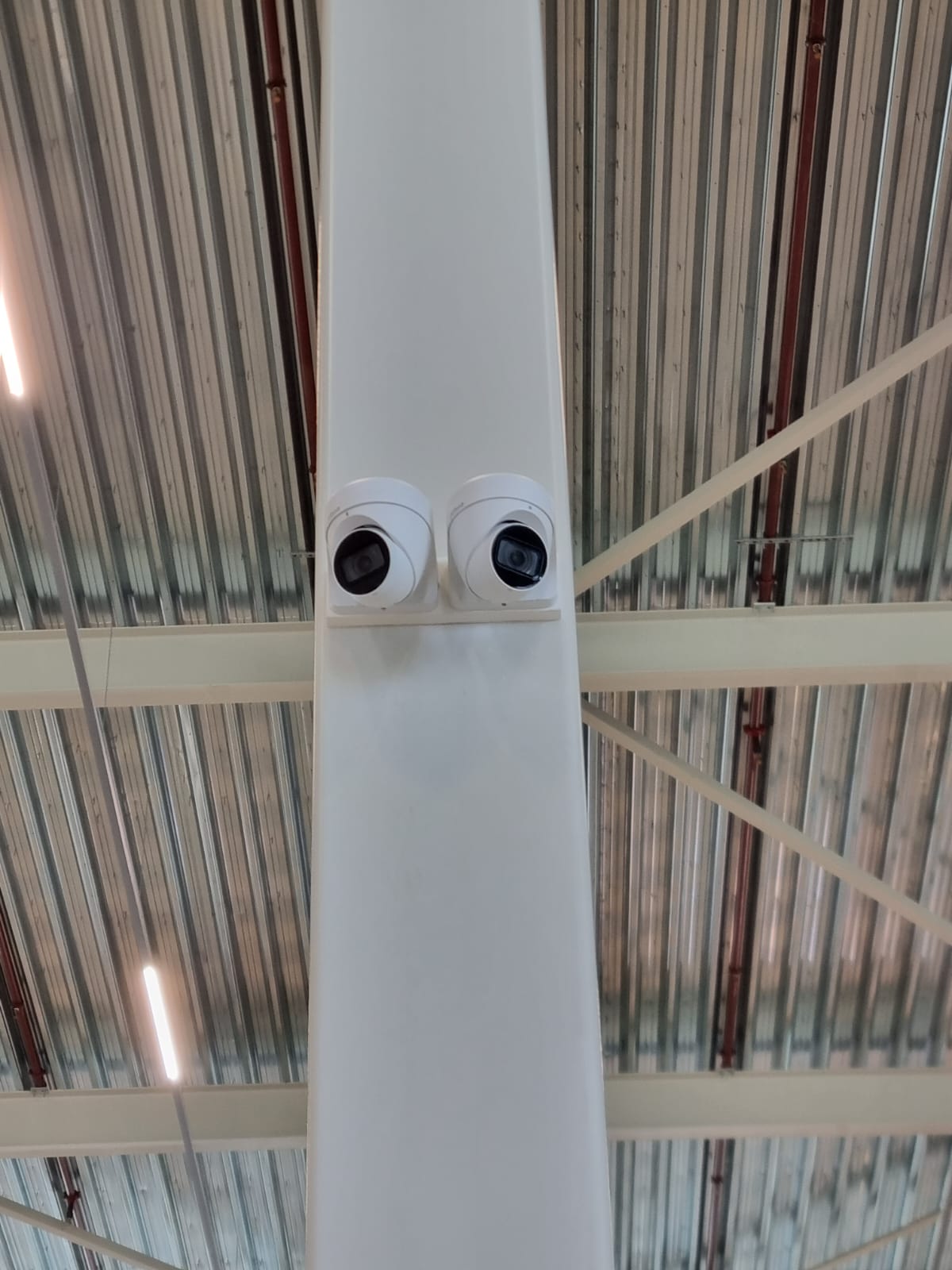 Twee turretcamera’s naast elkaar op een kolom onder het dak van een bedrijfshal