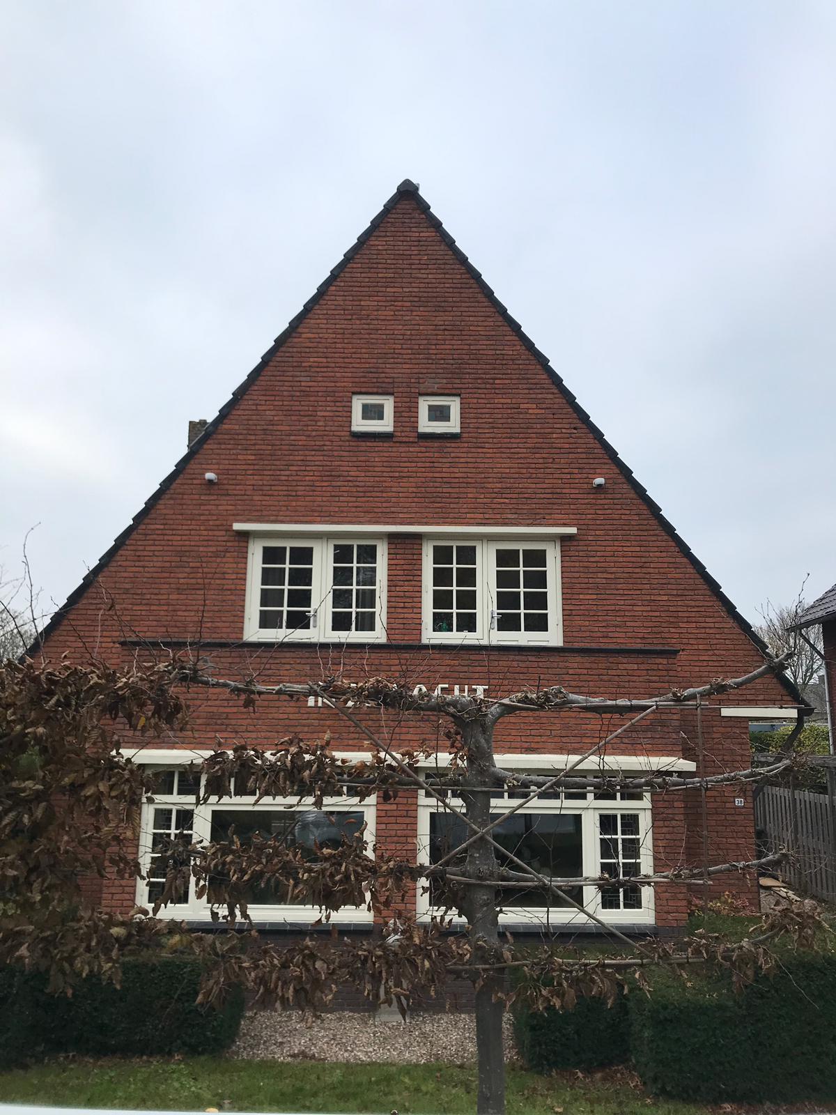 Woning met steile puntgevel, met aan beide zijden hoog onder het dak een bewakingscamera