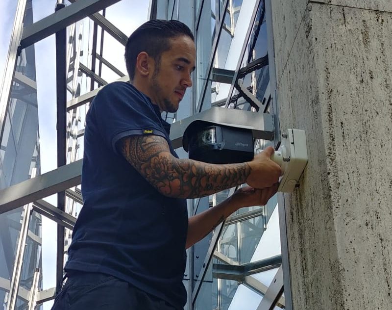 Monteur van CameraInstallatie.nl bevestigt een camera in een behuizing op een betonnen kolom