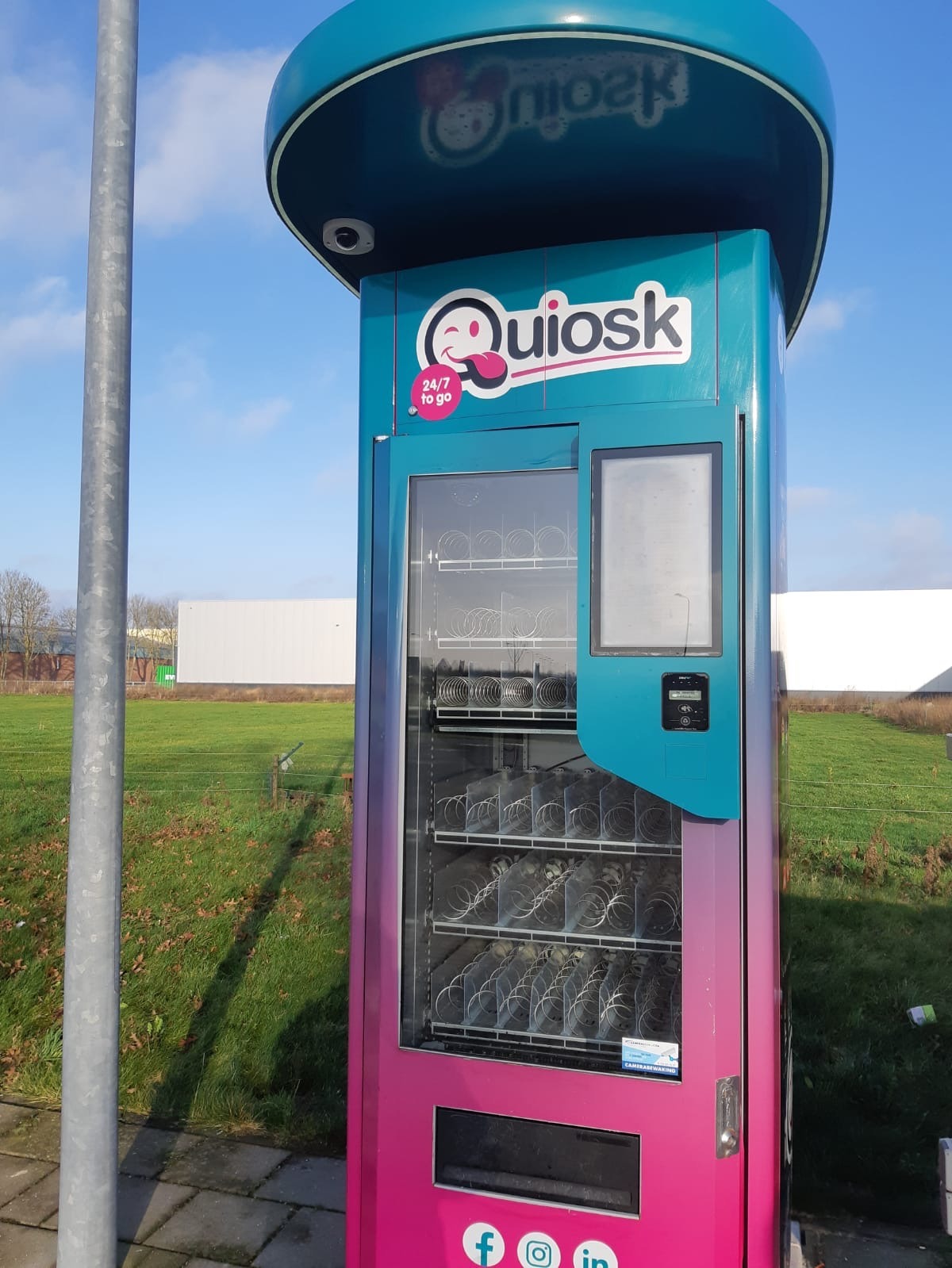 Onbemande snackautomaat langs een fietspad bij een grasveld