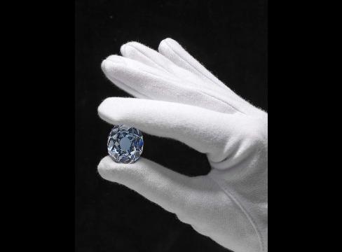 Sfeerbeeld: een geslepen blauwe diamant tussen witte handschoenen, symbool voor het beveiligen van waardevolle goederen