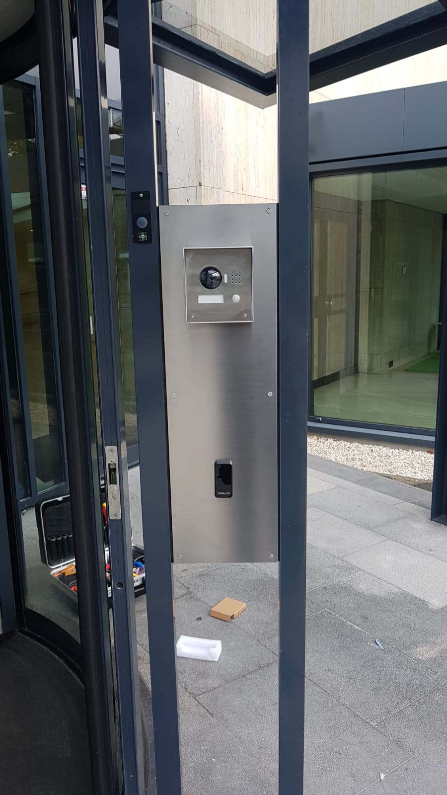 Roestvrijstalen zuil met deurstation en kaartlezer naast de glazen entreedeur van een appartementsgebouw