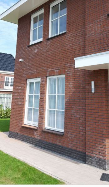 Witte beveiligingscamera hoog op de bakstenen gevel van een woonhuis