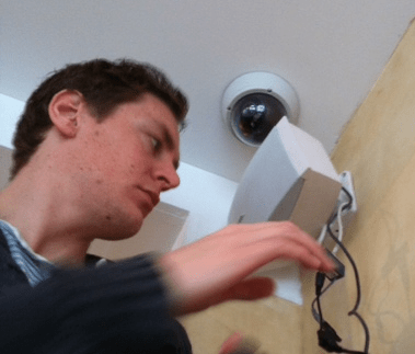 Monteur van CameraInstallatie werkt aan de recorder onder een witte dome-camera aan het plafond in de schoonheidssalon