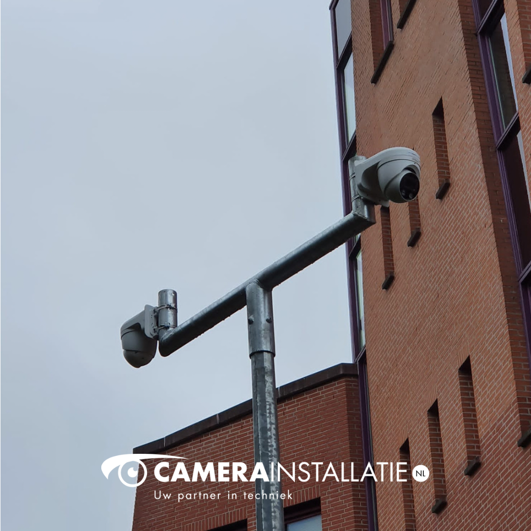 Twee turretcameras aan een mast bij een bakstenen kantoorpand