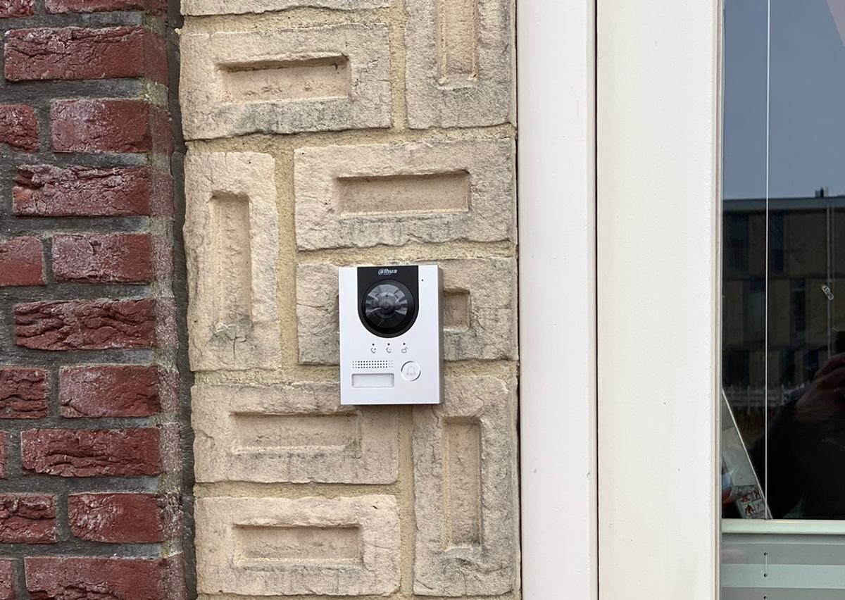Wit intercompaneel met camera, drie beldrukkers en een pasjeslezer op een natuurstenen deuromlijsting