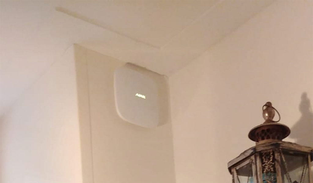 Witte centrale van Ajax met verlicht logo, hoog tegen een lichte wand in een hal gemonteerd