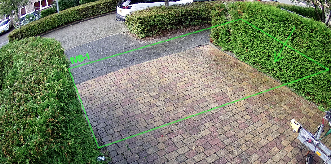 Camerabeeld van een oprit met een groene lijn en zone over de klinkers getekend