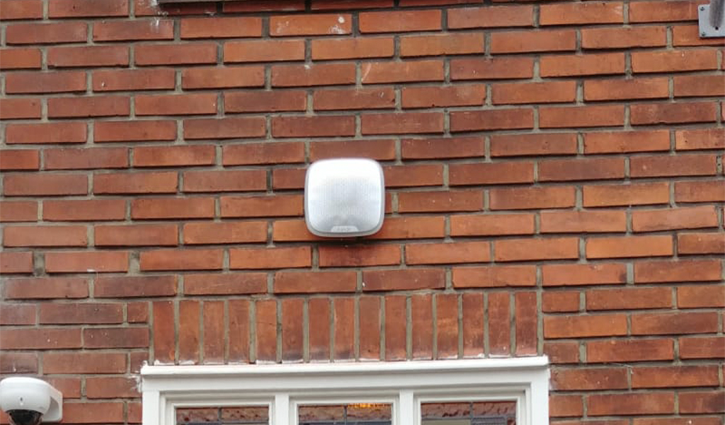 Witte buitensirene onder de dakrand van een woonhuis