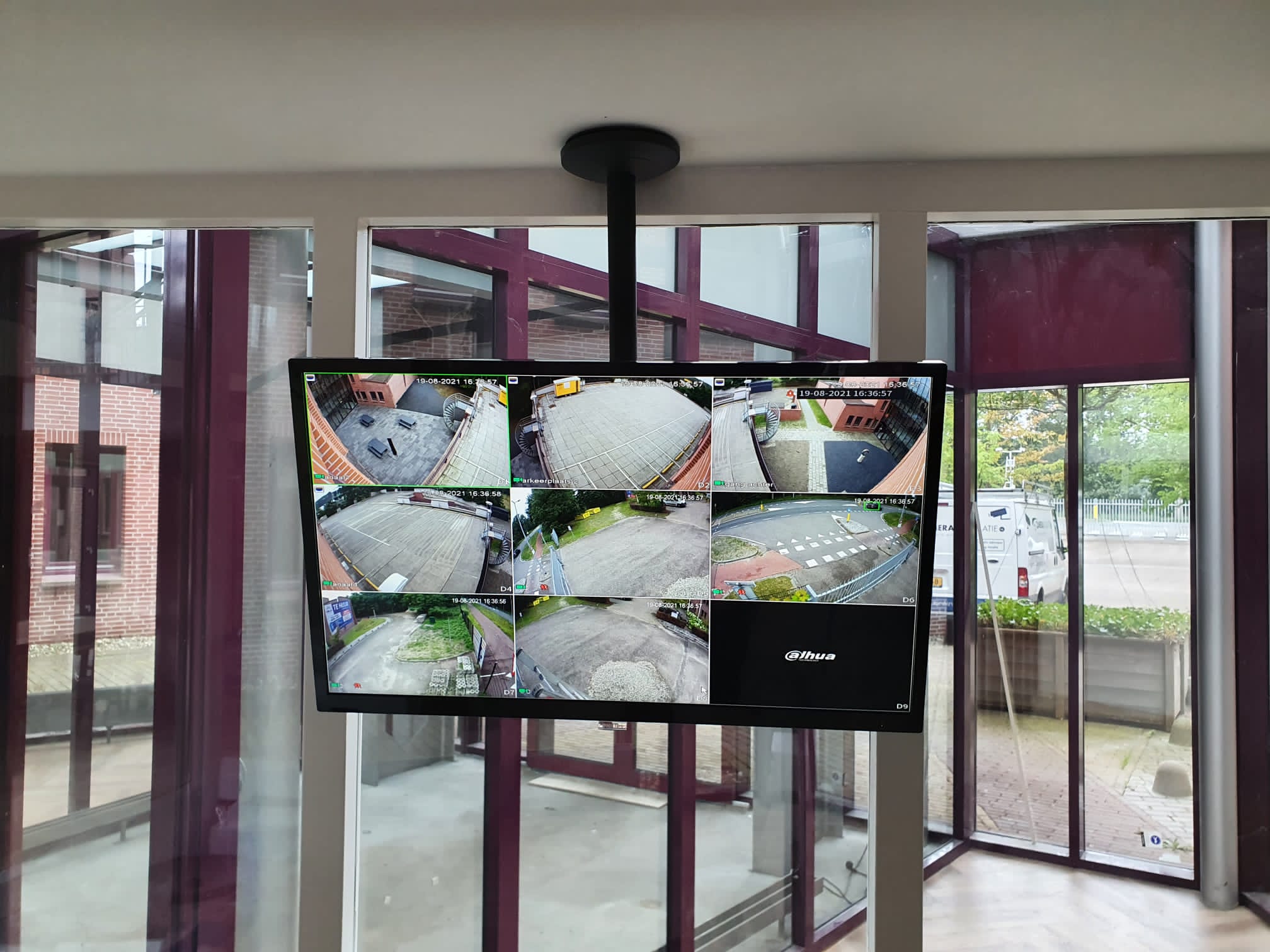 Aan het plafond gemonteerde monitor toont live de camerabeelden binnenshuis, met buiten de bus van CameraInstallatie zichtbaar