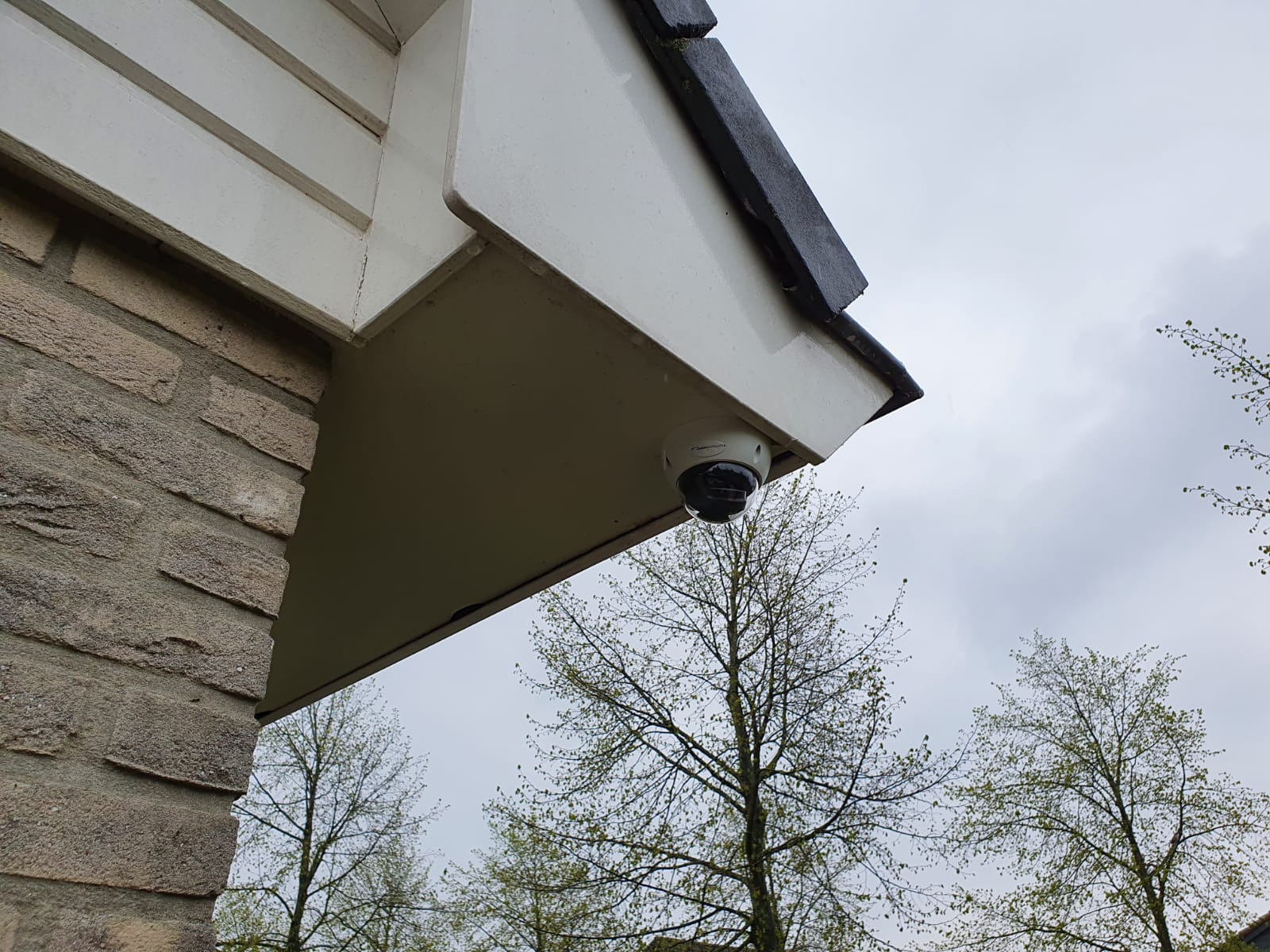 Witte dome-camera onder de witte onderkant van het dakoverstek van een woning in Zaandam