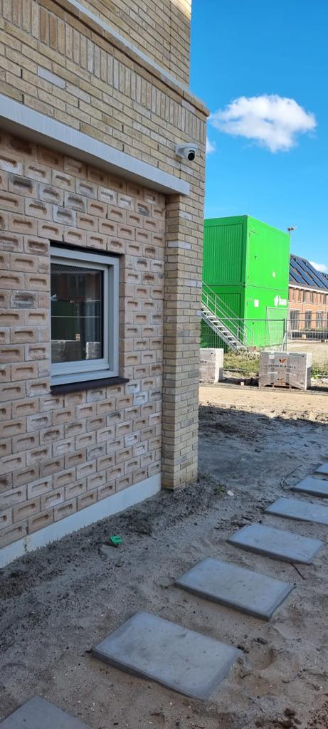 Camera hoog op de hoek van een nieuwbouwwoning met een tuin die nog niet is aangelegd