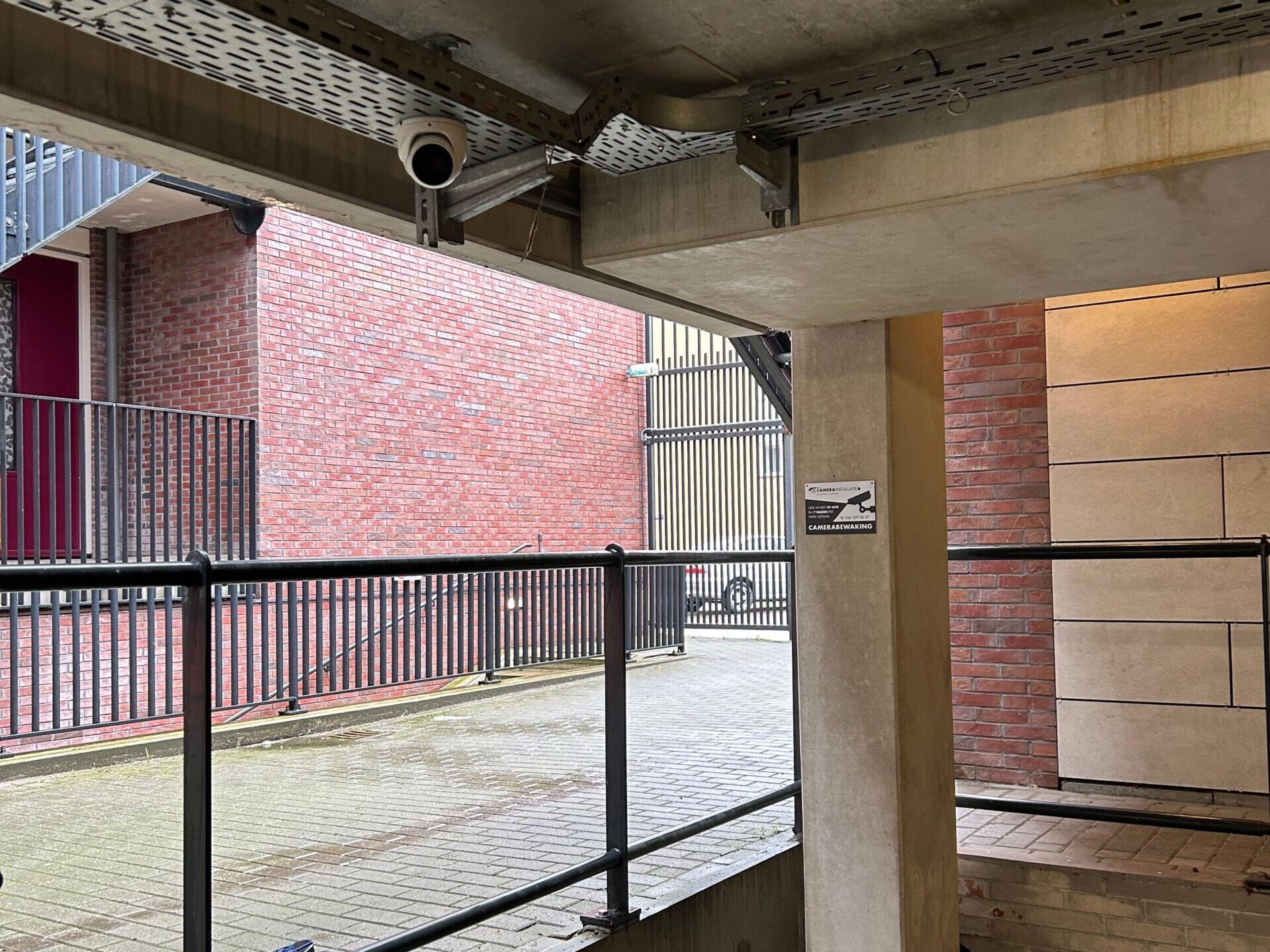 Bullet camera onder het betonnen parkeerdek met zicht op het binnenterrein