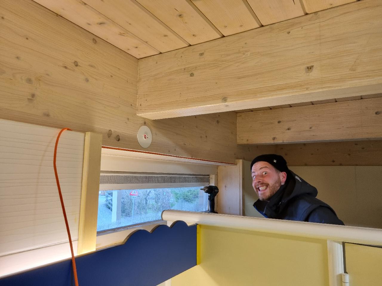 Lachende monteur van CameraInstallatie installeert een camera in een houten chalet op een camping