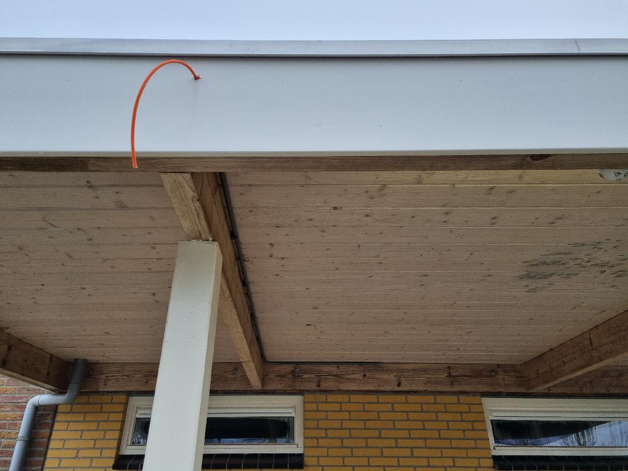Oranje kabel weggewerkt onder de overkapping van een campinggebouw