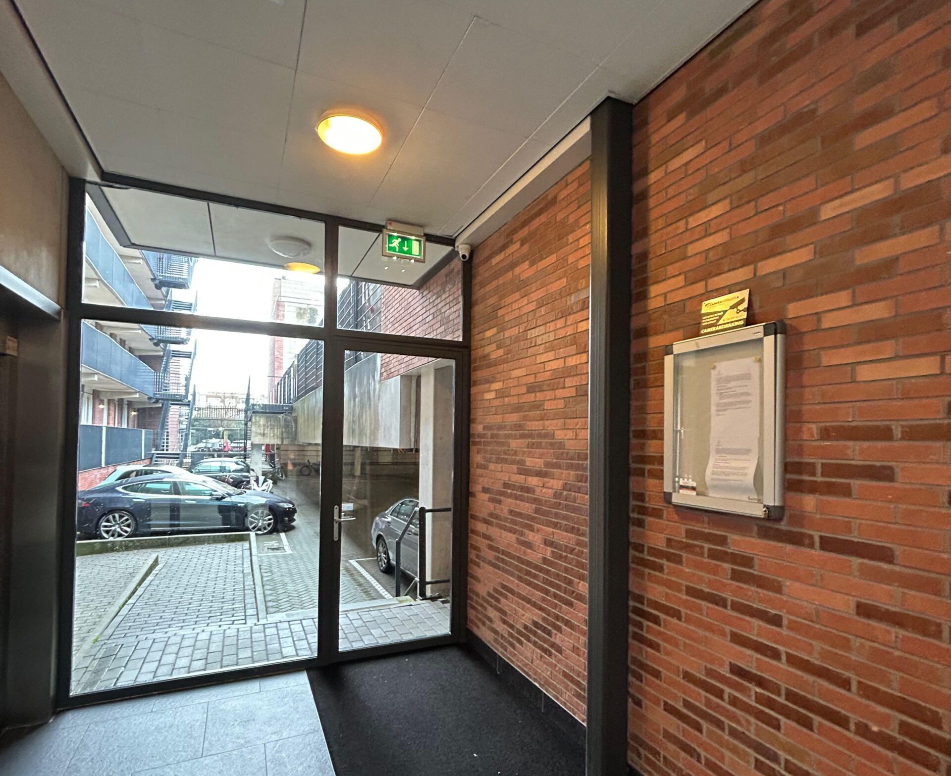 Portiek van het appartementencomplex met glazen pui en zicht op het binnenterrein