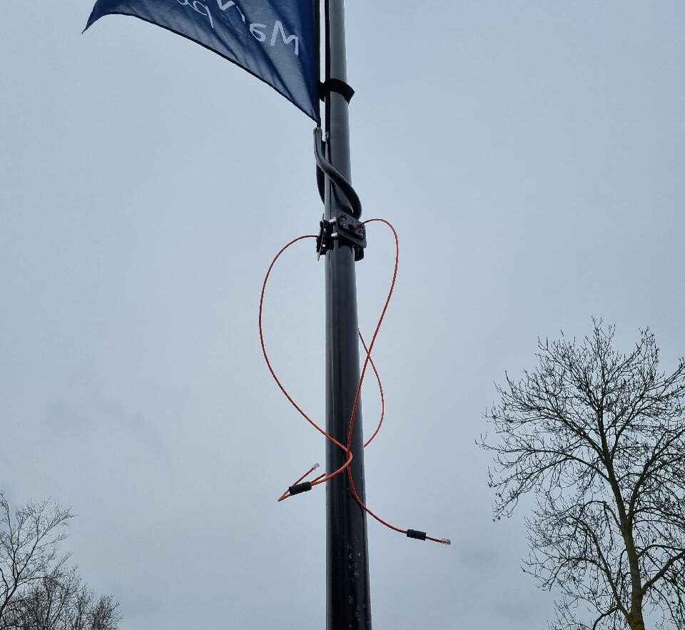 Beugel met een oranje netwerkkabel rond de vlaggenmast, klaar voor de camera’s