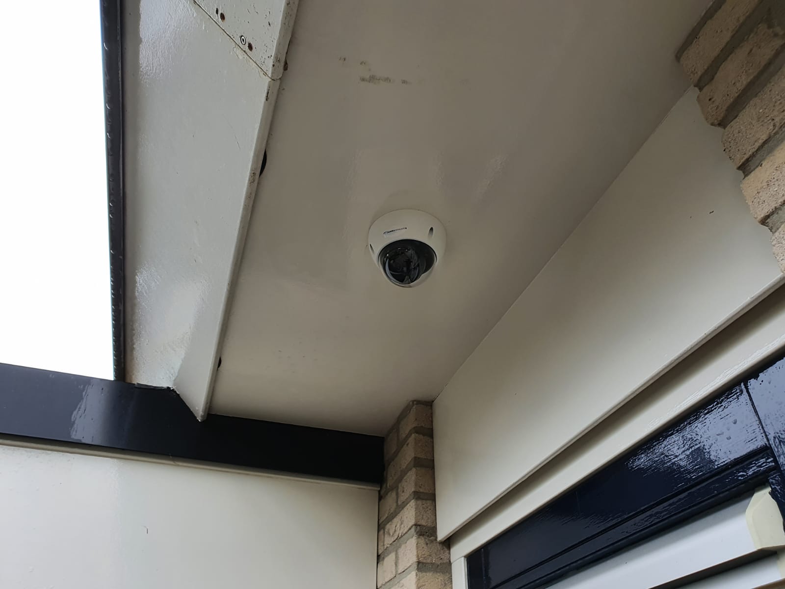 Witte domecamera in het plafond van een overkapping bij een woning
