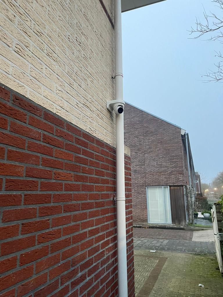 Beveiligingscamera aan de hoek van een woning, gericht langs de eigen gevel en het pad in plaats van de straat in