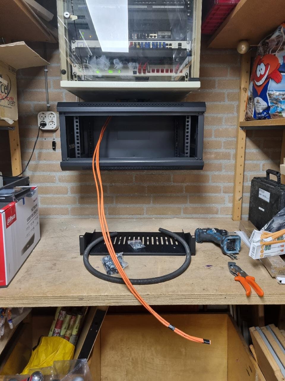 Werkbank met gereedschap en een oranje netwerkkabel onder de wandkast in de techniekruimte