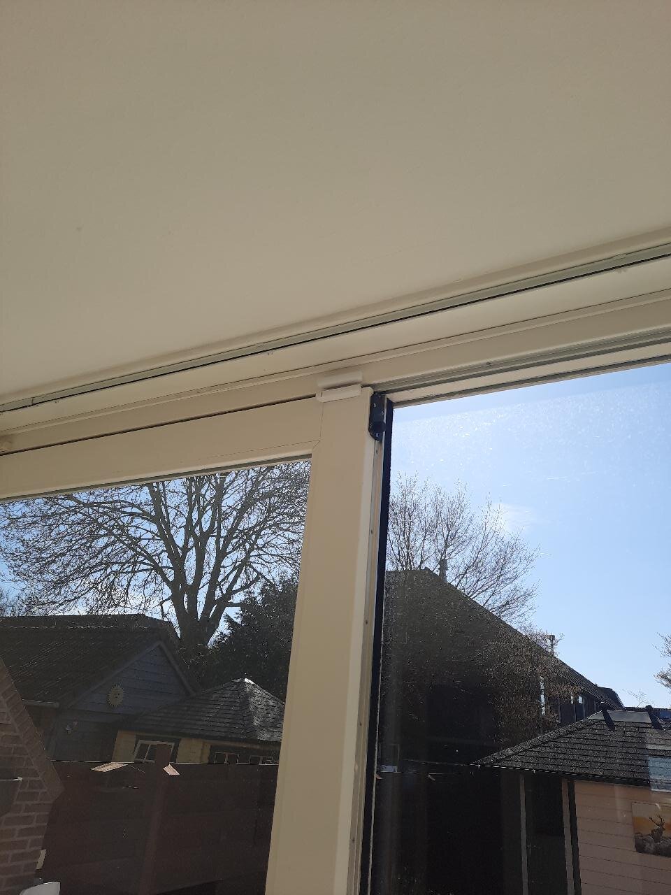 Detail van een contactmelder bovenaan de hoek van de grote schuifpui in de woning