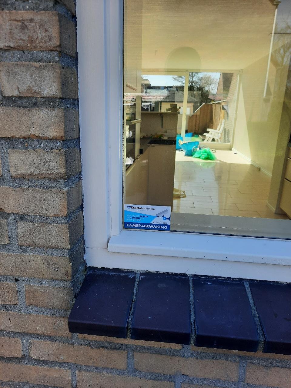 Raamsticker Camerabewaking van CameraInstallatie.nl op het raam van de woning, met zicht op de keuken en de tuin erachter