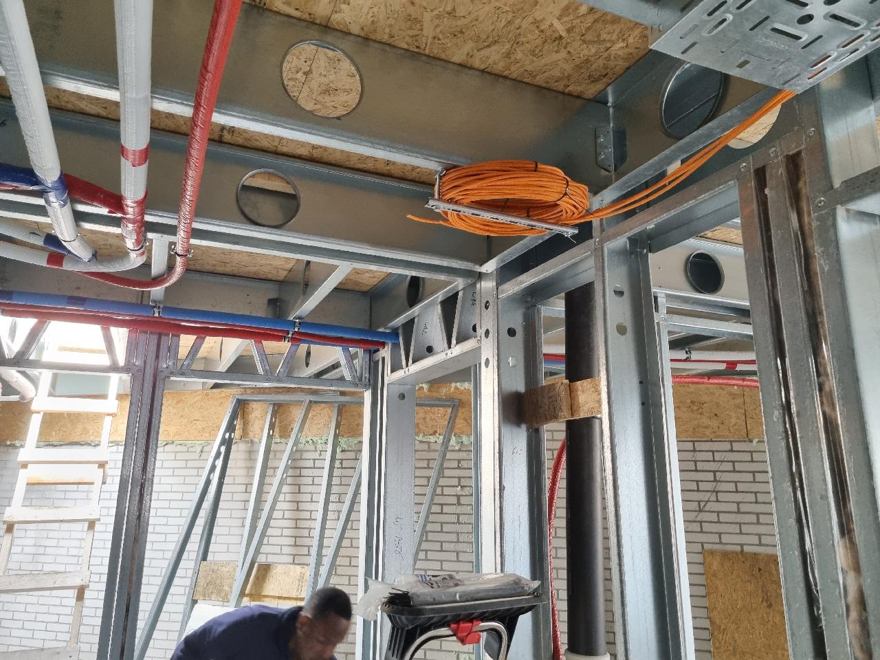 Monteur van CameraInstallatie werkt aan de bekabeling in een woning in aanbouw met stalen frame