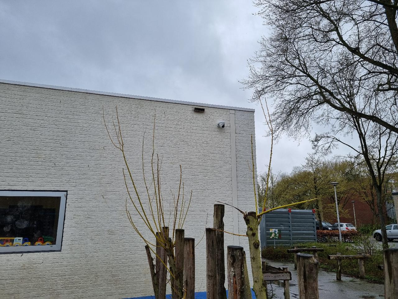 Camera hoog op de witte blinde gevel van een school in Zwolle, boven het speelplein