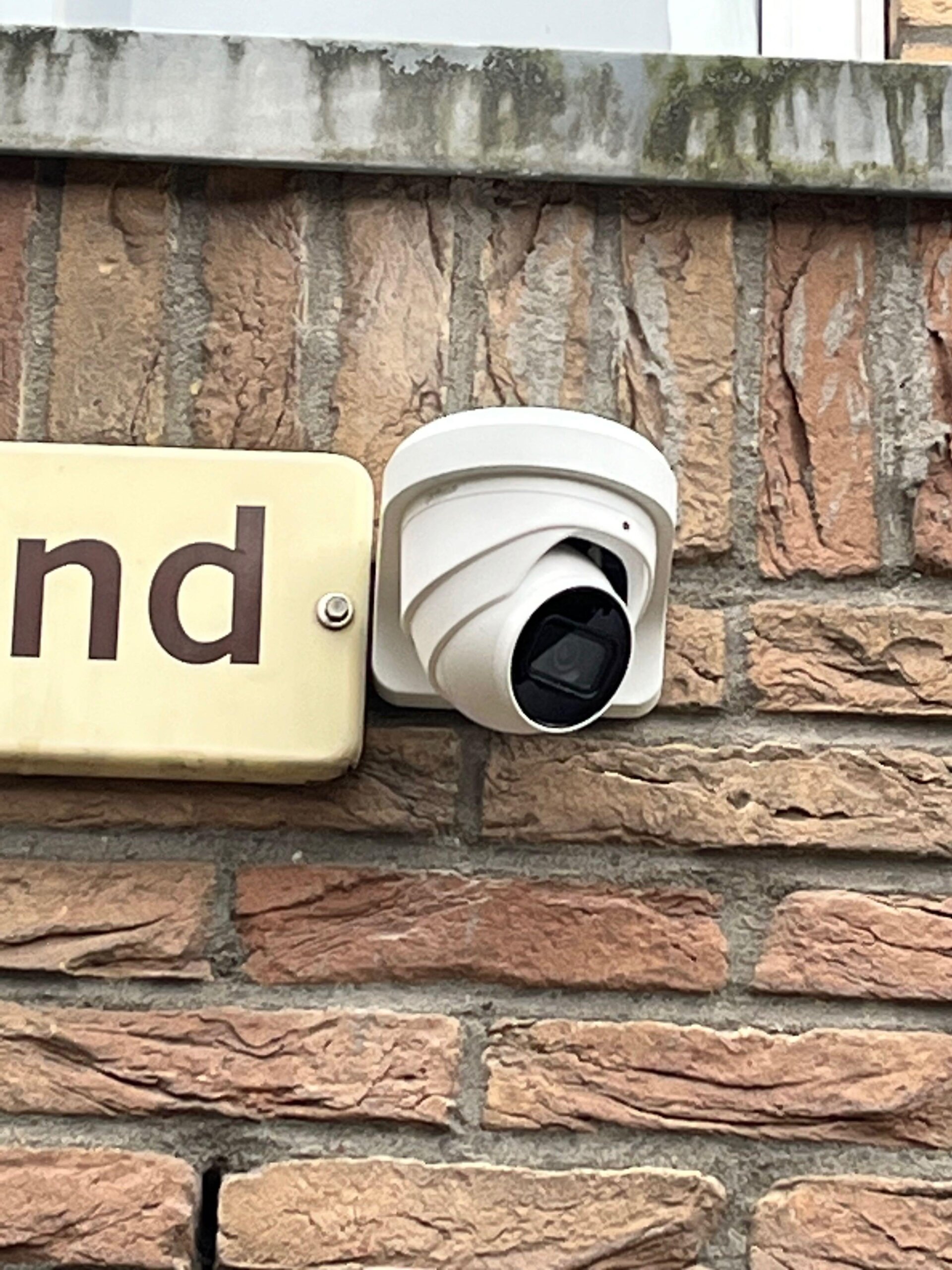 Witte Dahua-camera plat tegen de bakstenen gevel van een woning in Diemen