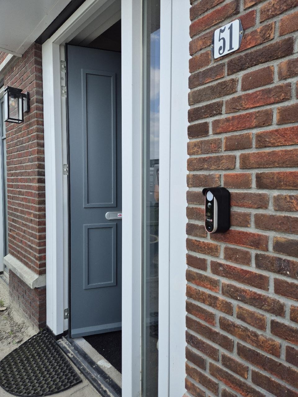 Digitale deurbel met camera gemonteerd naast de voordeur van een woning