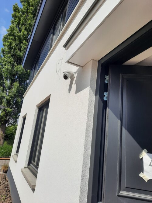 Witte Dahua turret-camera netjes gemonteerd op de lichte gevel naast de nog met folie beplakte nieuwe voordeur van de woning