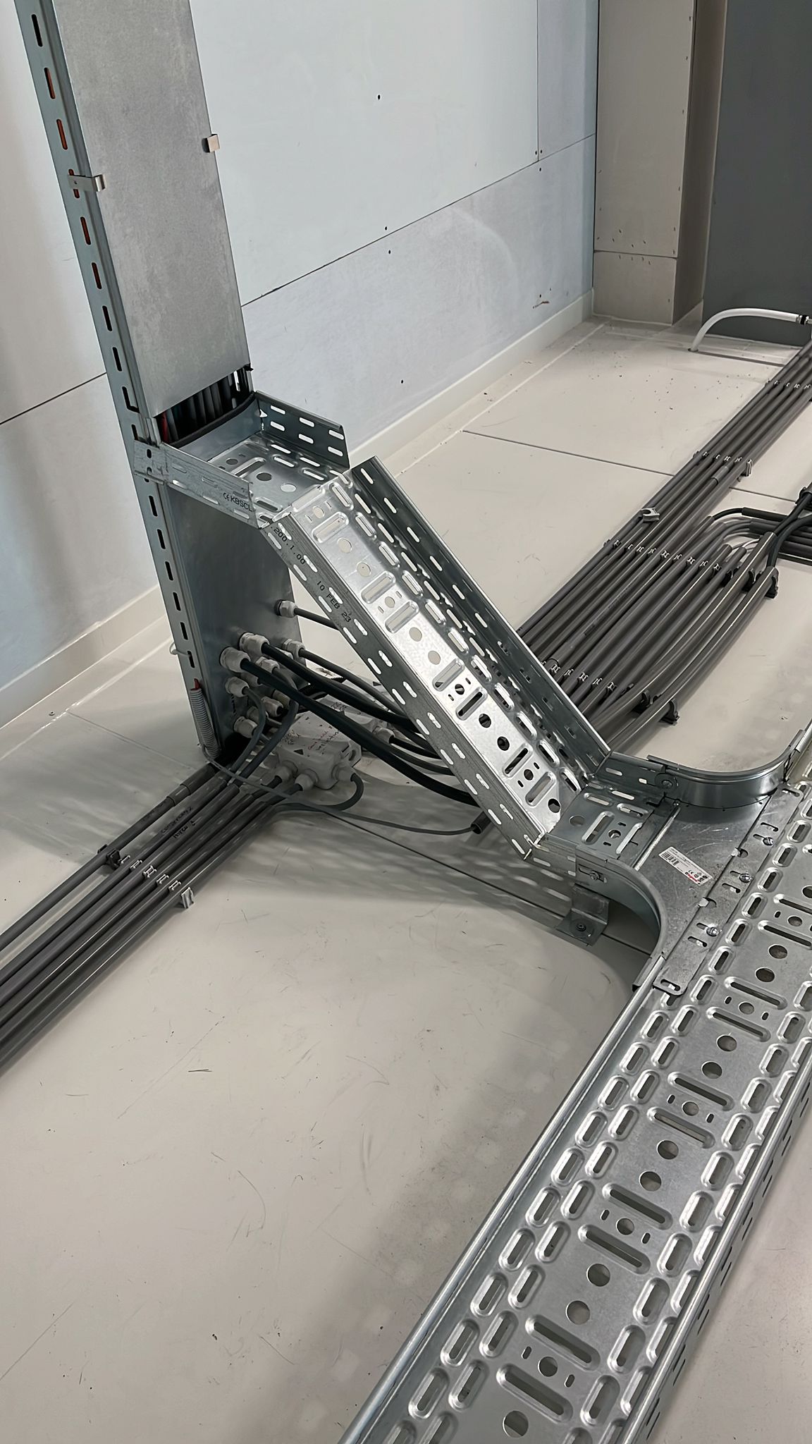 Metalen kabelgoten met netjes weggewerkte data- en voedingskabels langs vloer en wand