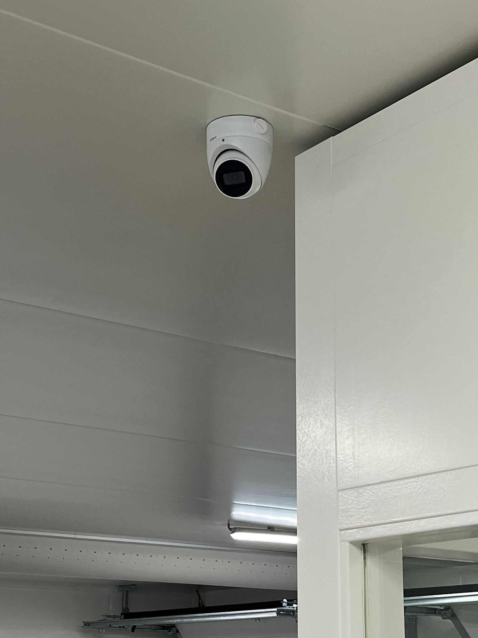 Twee monteurs van CameraInstallatie werken aan een geopende patchkast vol netwerkbekabeling