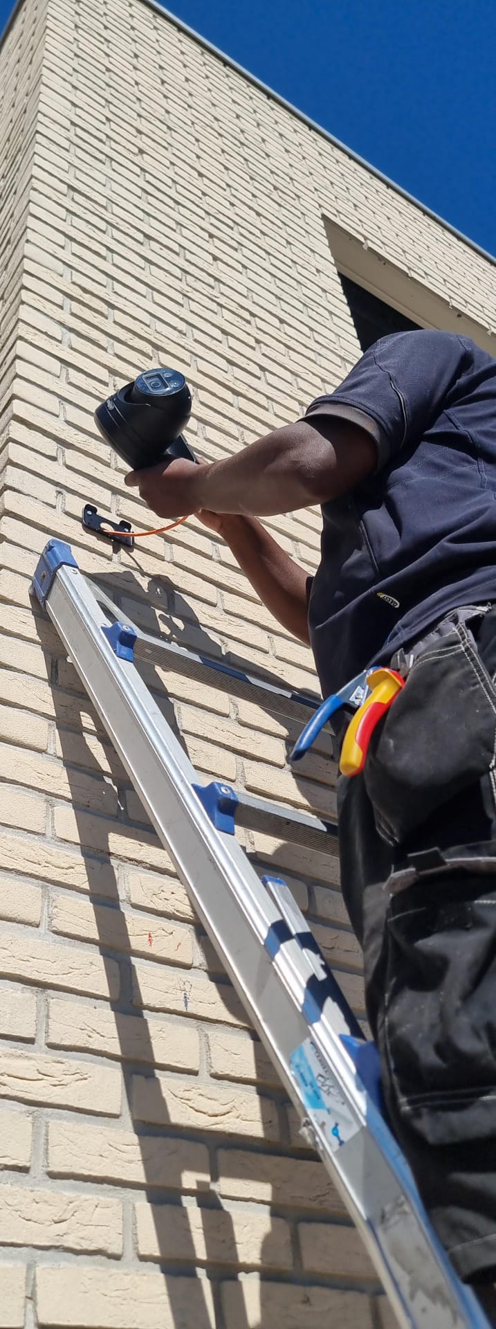 Monteur van CameraInstallatie installeert vanaf een ladder een Dahua-camera aan de gevel van de egelopvang