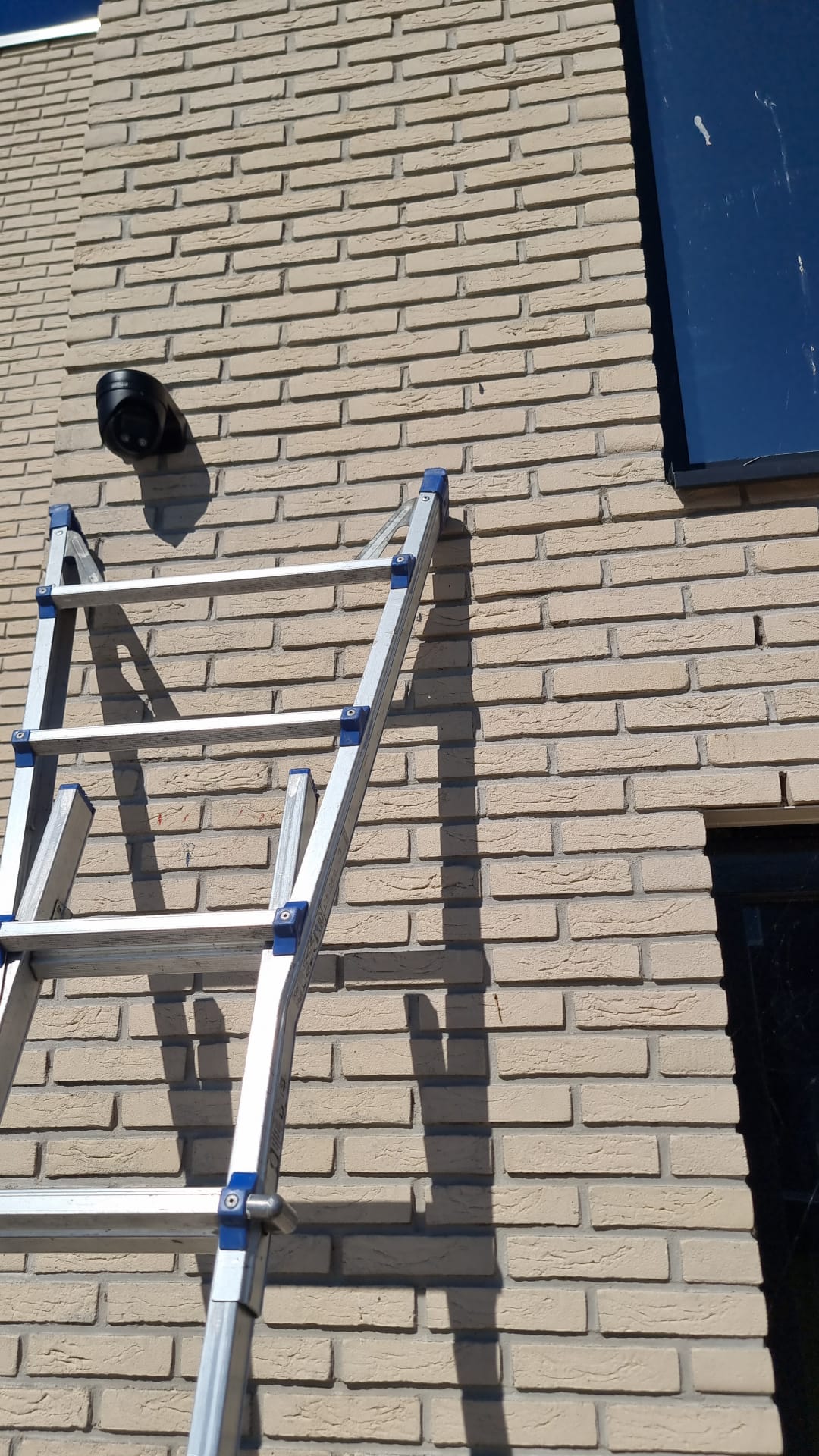 Zwarte Dahua-camera strak gemonteerd op de gevel, met de ladder ernaast tijdens de installatie