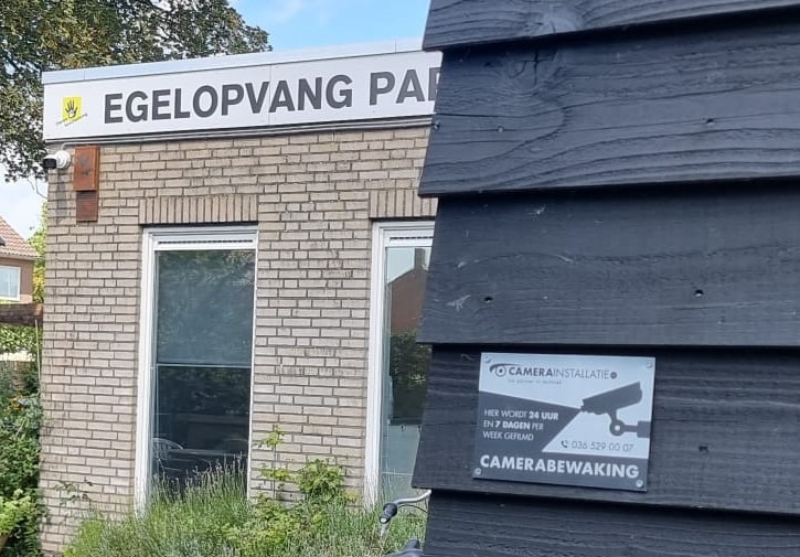 Bijgebouw van de egelopvang met een bord van CameraInstallatie waarop staat dat er 24 uur per dag wordt gefilmd
