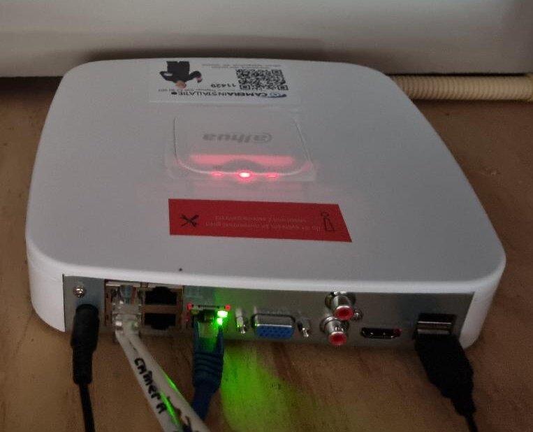Witte Dahua-netwerkrecorder met aangesloten netwerkkabels en een servicesticker van CameraInstallatie