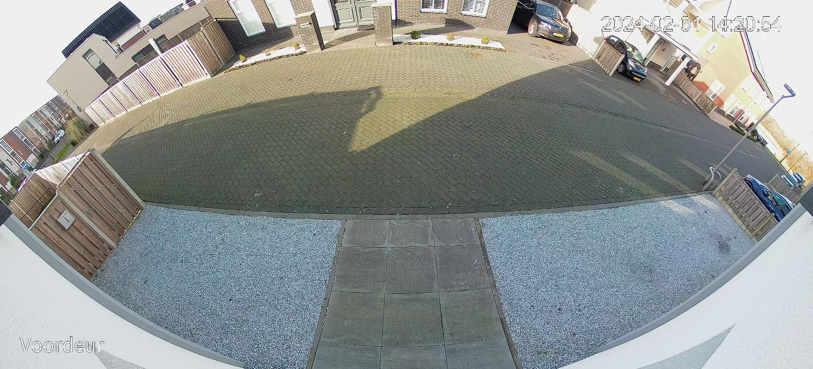Panoramisch camerabeeld van de voorzijde: oprit, bestrating en de straat met geparkeerde auto's, in een breed 180-gradenvlak