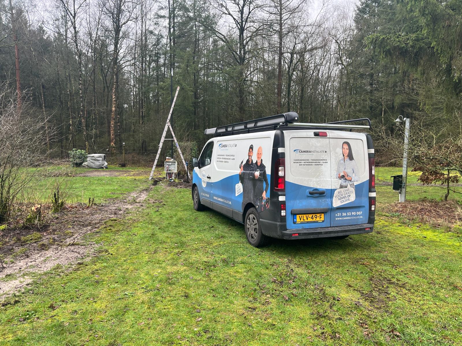 Bus van CameraInstallatie geparkeerd op het grasveld van het recreatieterrein, met een ladder klaar op de achtergrond