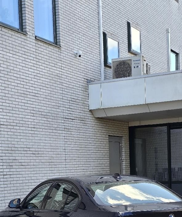 Dome-camera aan een lichte bakstenen gevel boven de zij-ingang van een bedrijfspand