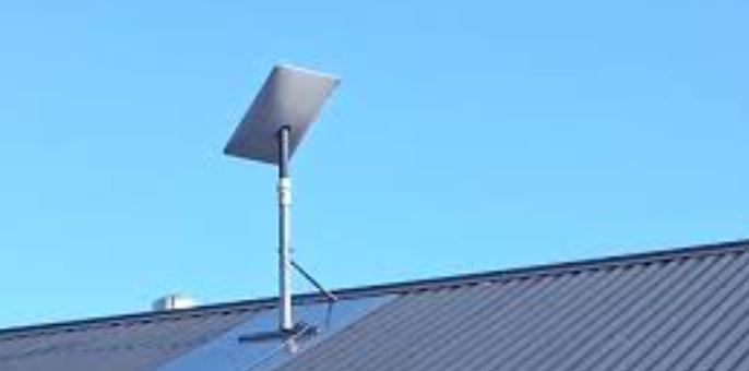 Satellietschotel op een paal met driepoot, geplaatst op de nok van een dak met damwandprofielplaten