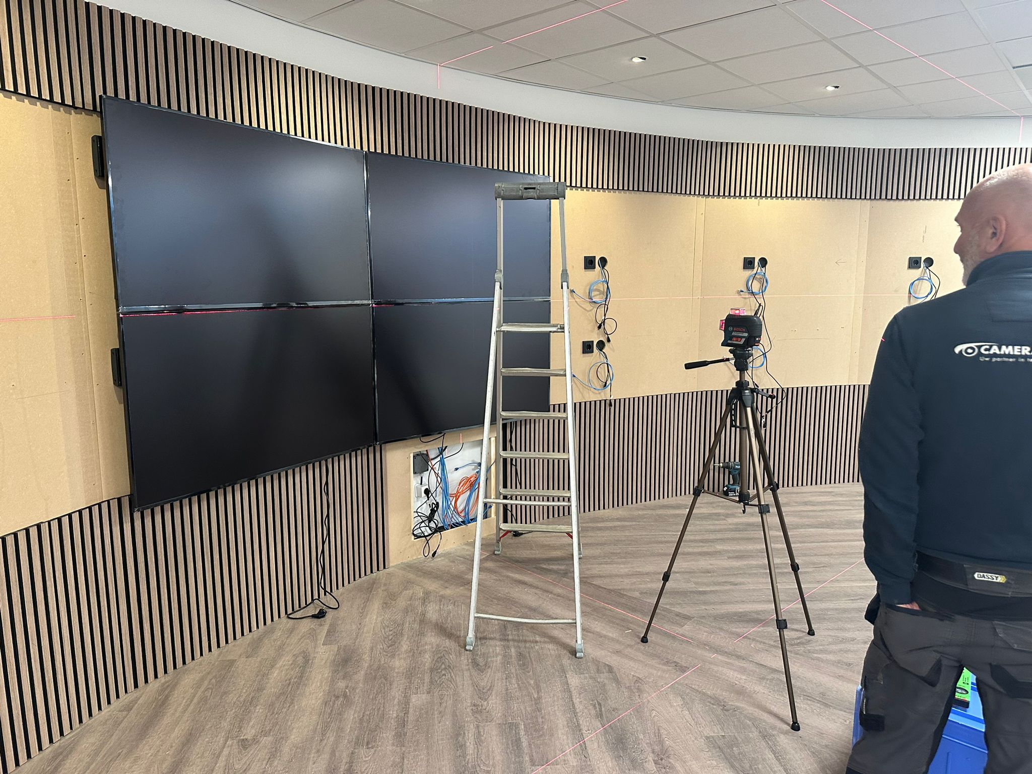 Monteur van CameraInstallatie lijnt met een Bosch-laserwaterpas de eerste schermpanelen uit op de gebogen wand