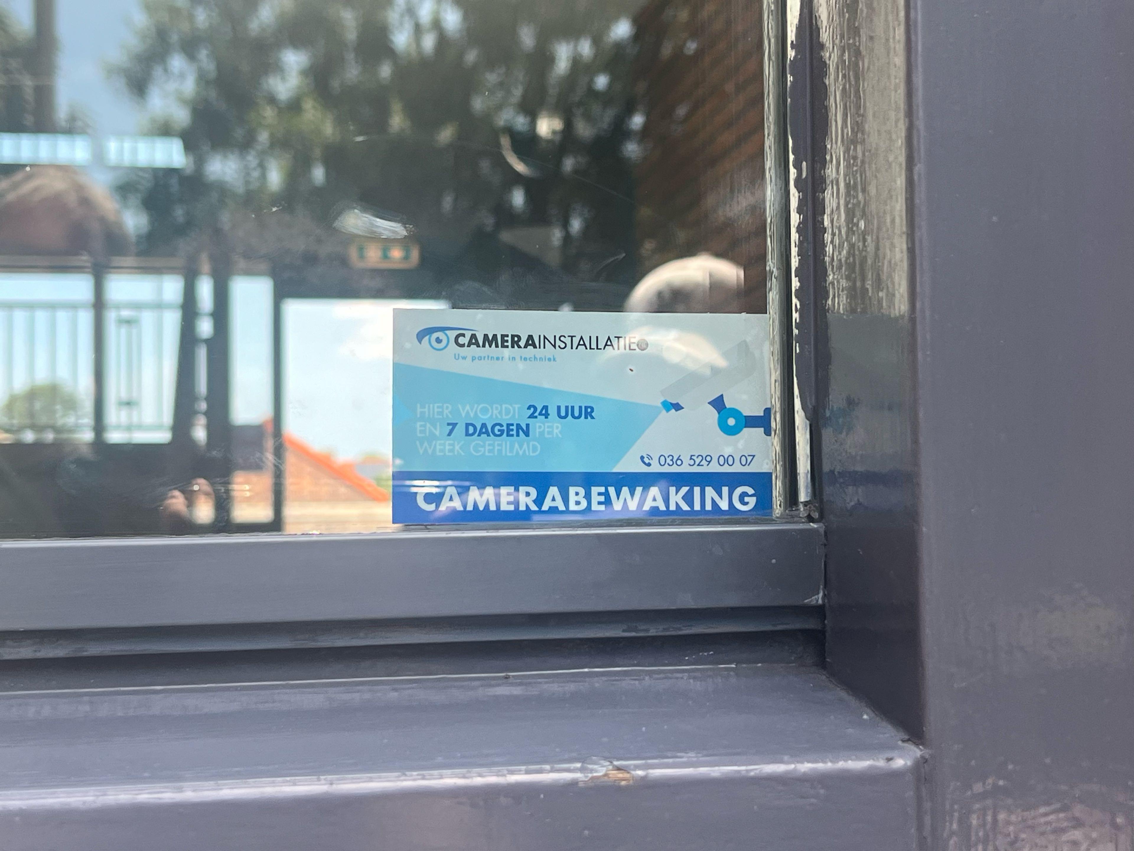 Sticker van CameraInstallatie op een ruit met de tekst hier wordt 24 uur en 7 dagen per week gefilmd