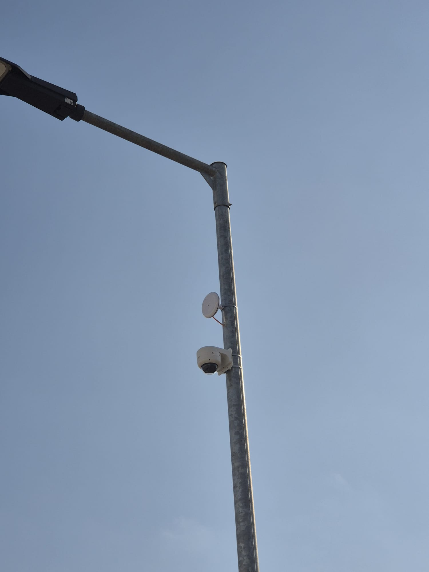 Bestaande lichtmast met een draadloze zender en een koepelcamera halverwege de mast