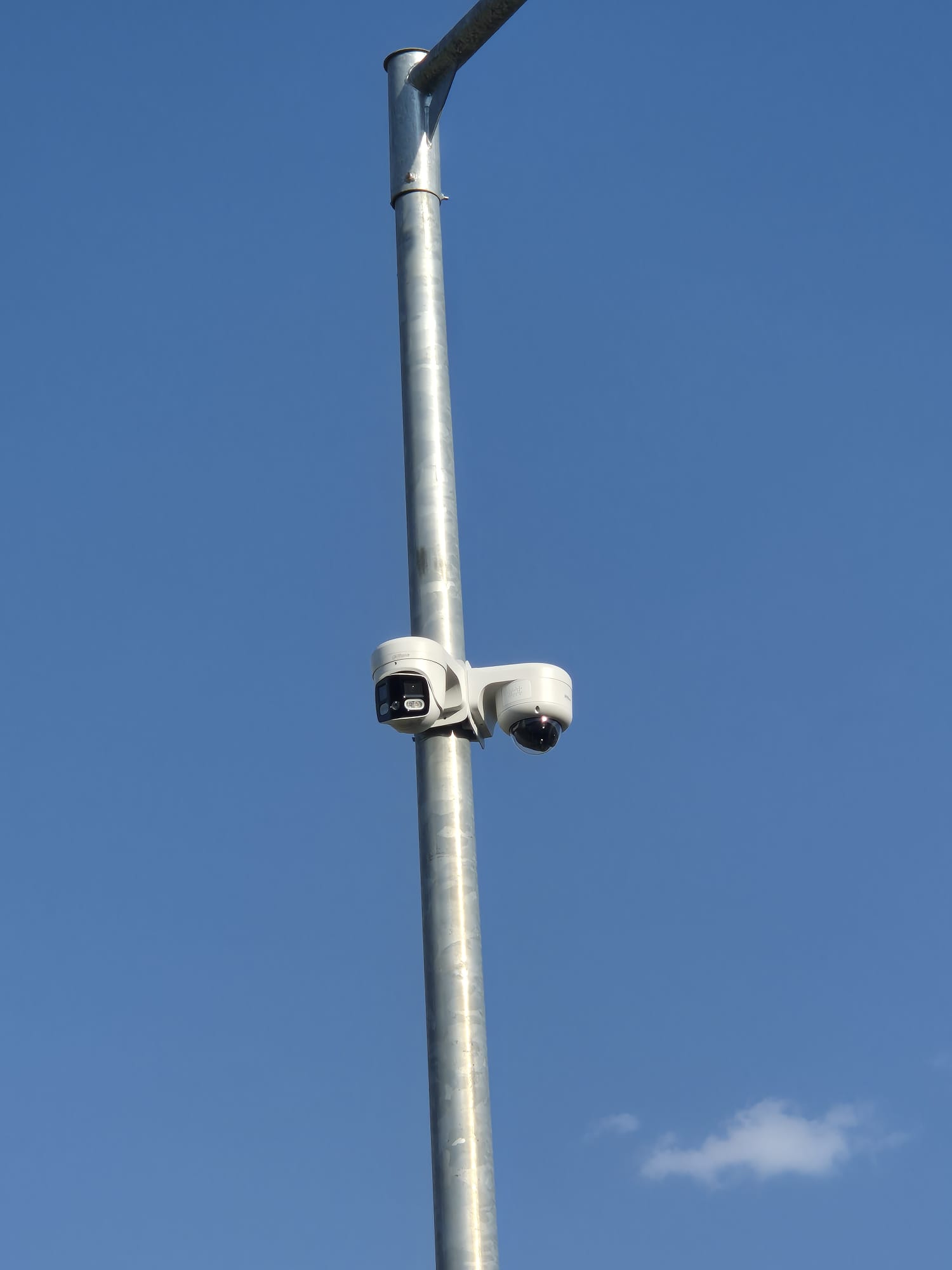 Twee camera's onder elkaar op een verzinkte paal tegen een blauwe lucht