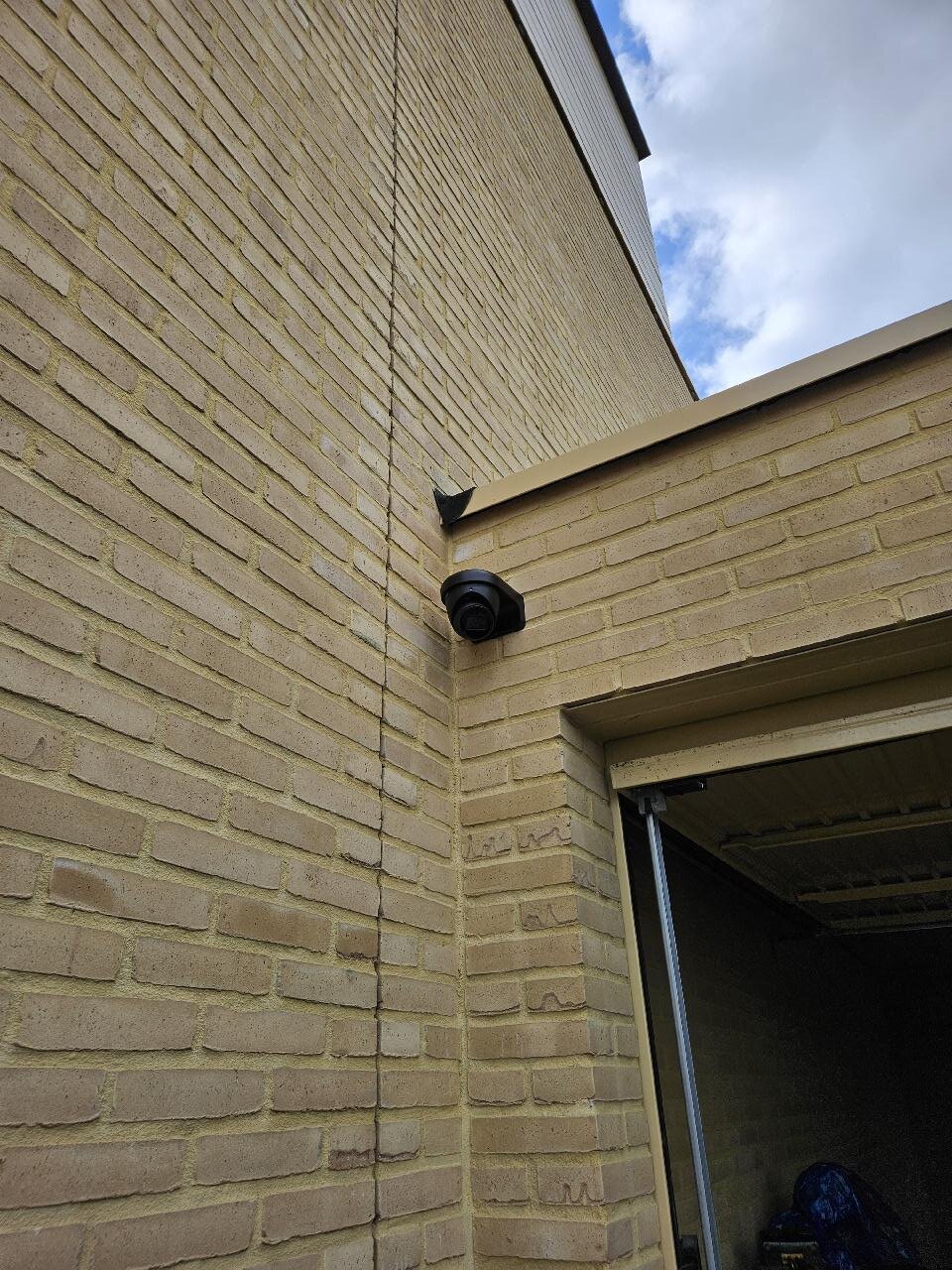 Detail van een zwarte Dahua dome-camera op de hoek van een woning, kabel volledig weggewerkt