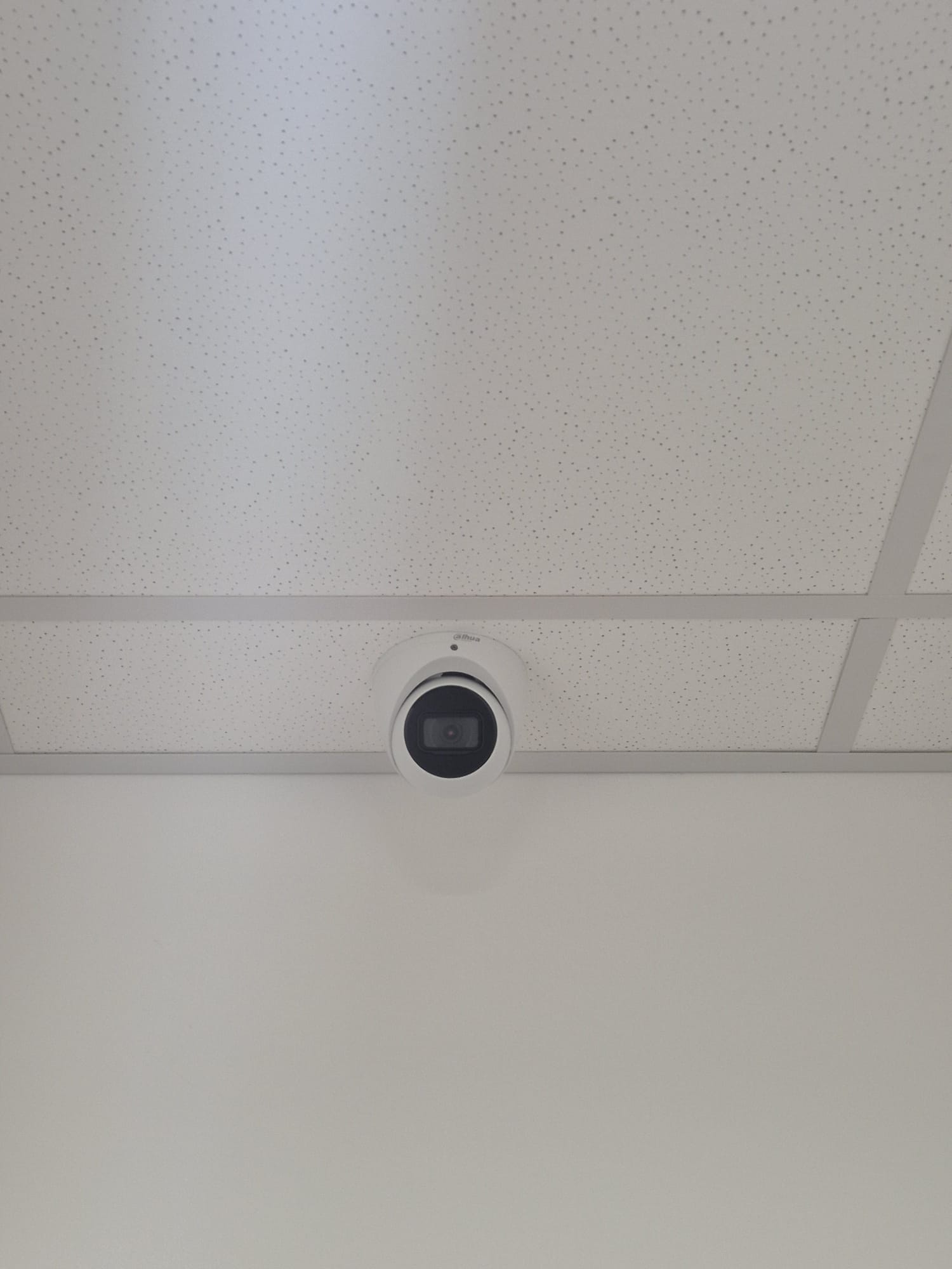 Witte koepelcamera weggewerkt in een wit systeemplafond van een kantoorruimte