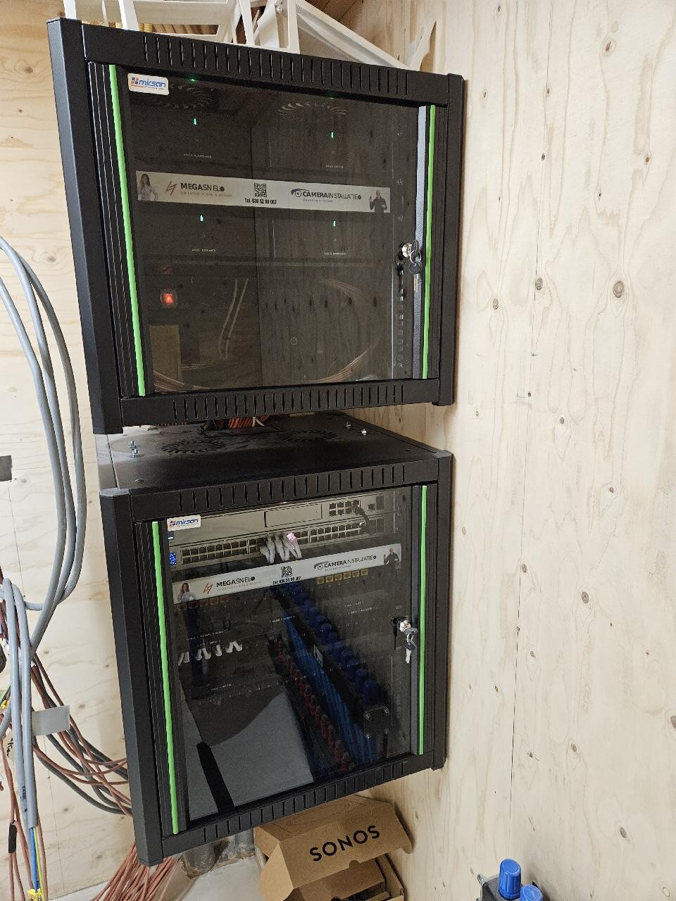 Twee afsluitbare wandkasten boven elkaar in de technische ruimte, met links een bundel binnenkomende kabels
