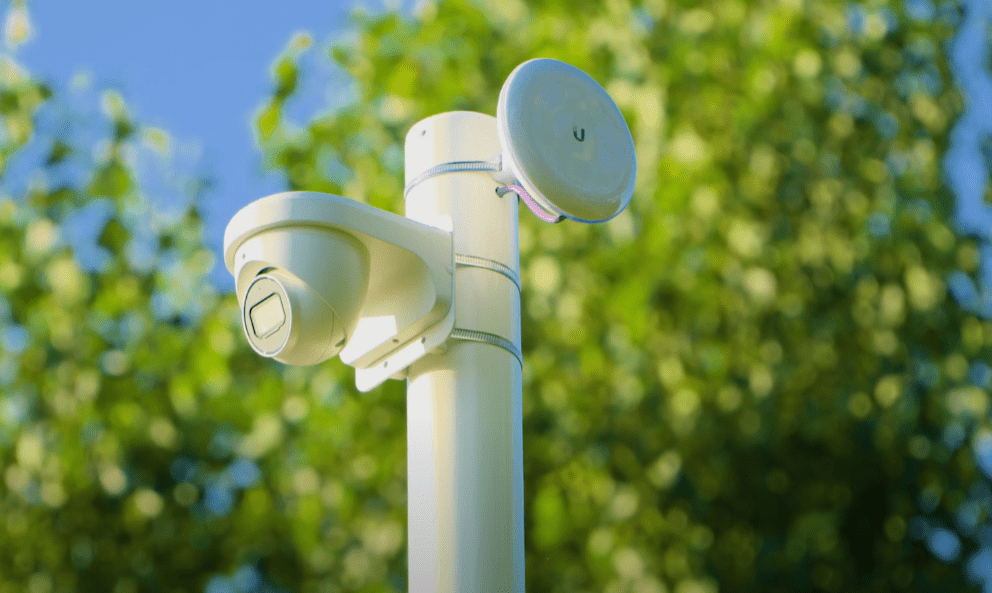 Witte dome-camera en een draadloze straalzender samen op een witte paal tussen de bomen op het terrein van de Keukenhof
